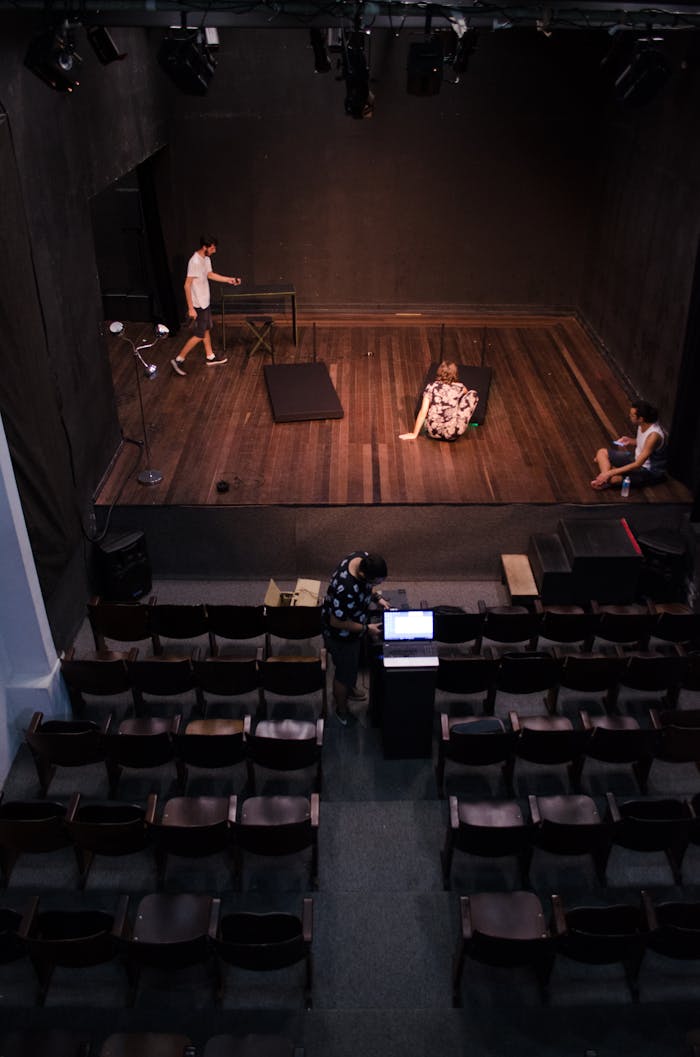 Actors rehearsing on stage in an empty theater, viewed from above.